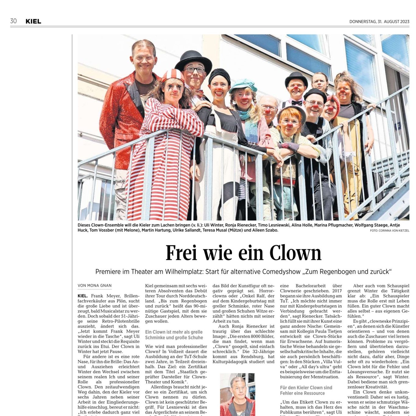 Gruppe von Menschen in bunten Kostümen, die auf einem Balkon stehen und lächeln.